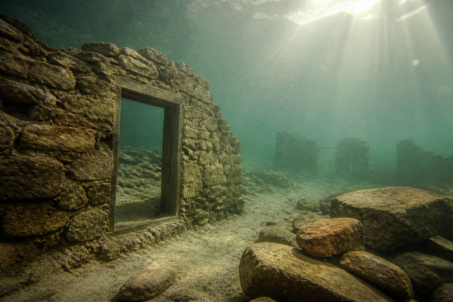 Ruines de village englouti visibles sous la surface claire du lac